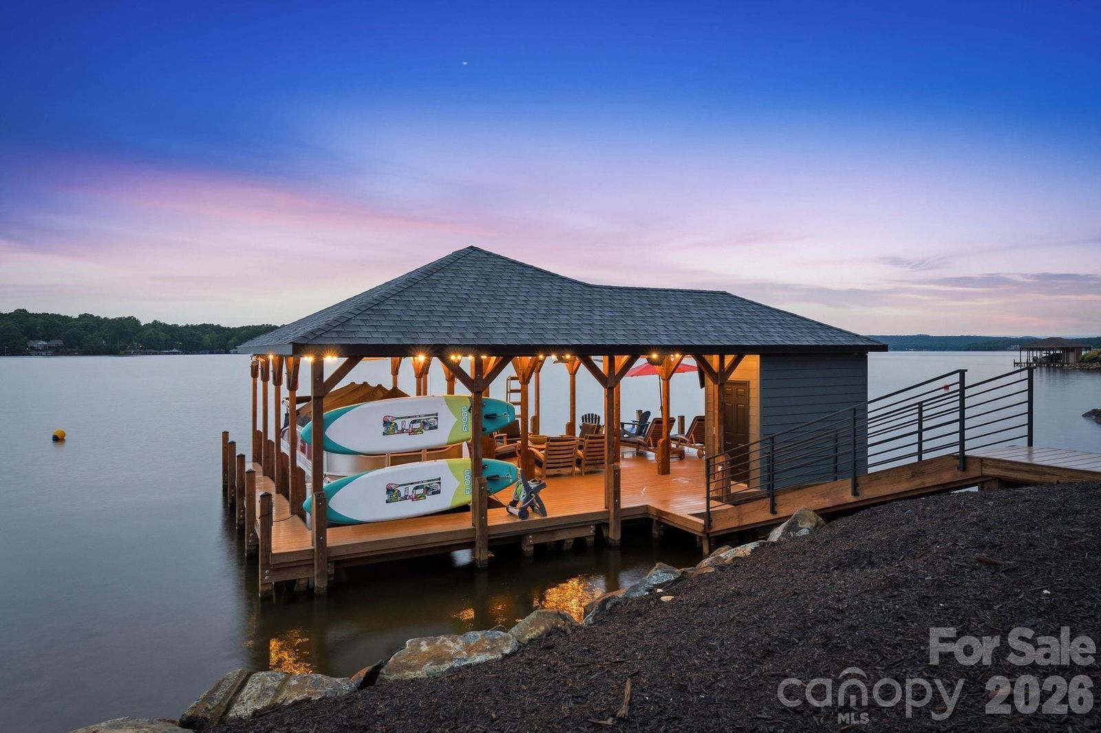 Private boathouse at 123 Cove Point on Lake Tillery at dusk, with a lounge area and boat lift