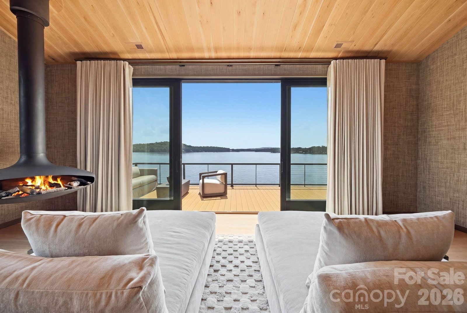 Primary suite at 123 Cove Point with a suspended Gyrofocus fireplace and glass doors to a lakeside deck