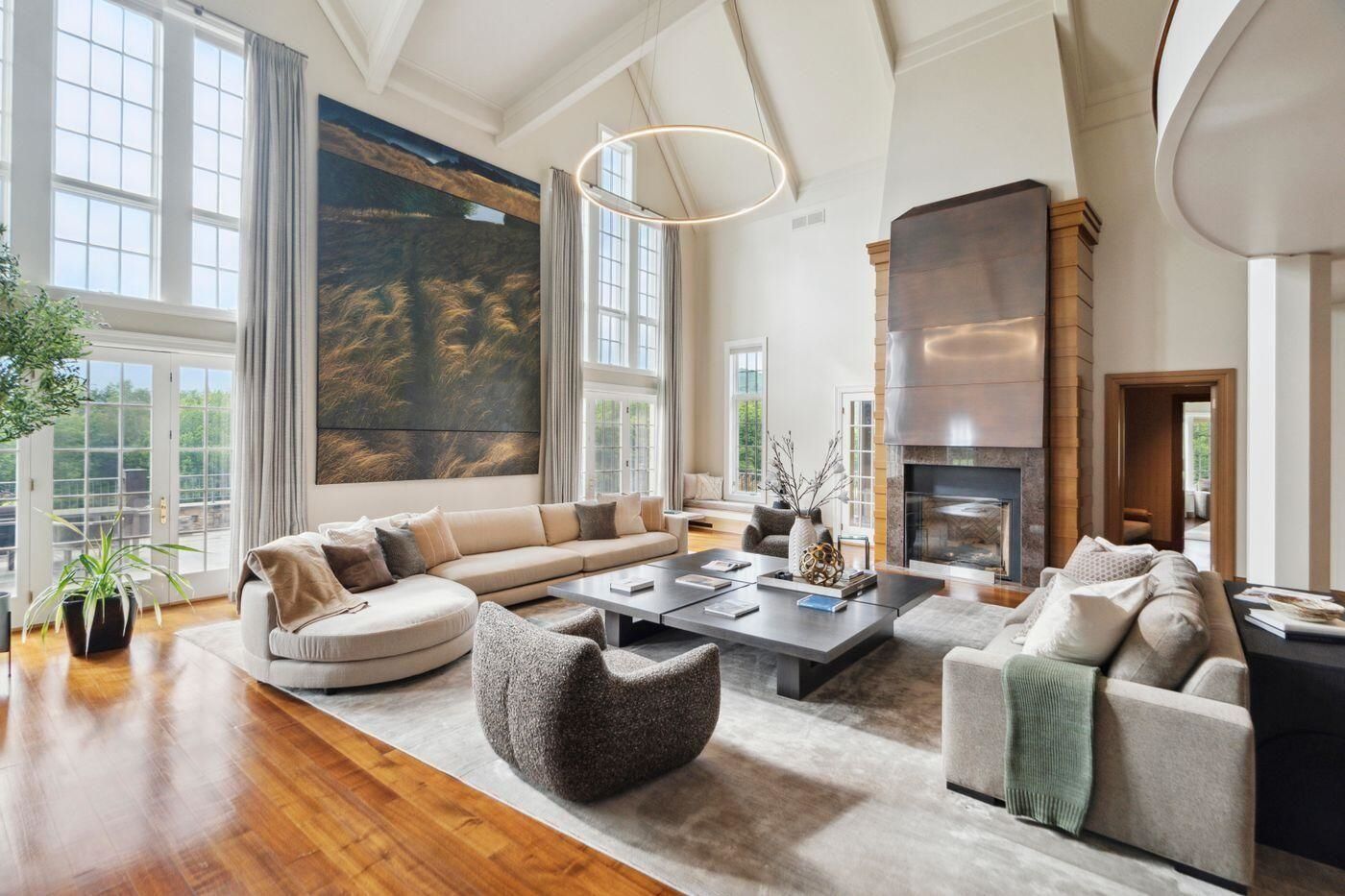Two-story great room with tall windows, fireplace, and seating area at 2575 Weeks Hill Road, Stowe, Vermont
