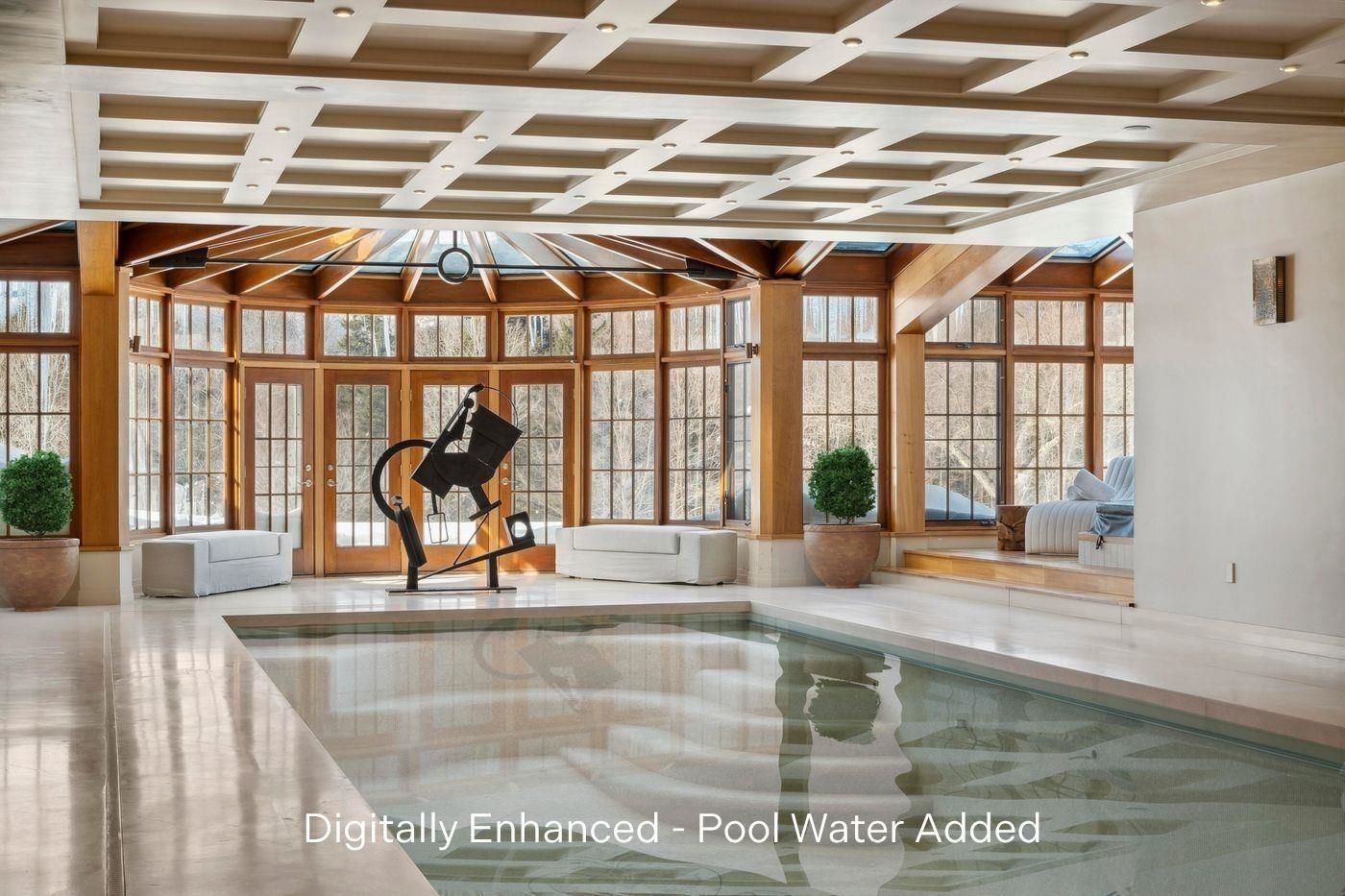 Indoor pool with tile and travertine surround under a coffered ceiling and glass walls at 2575 Weeks Hill Road, Stowe, Vermont