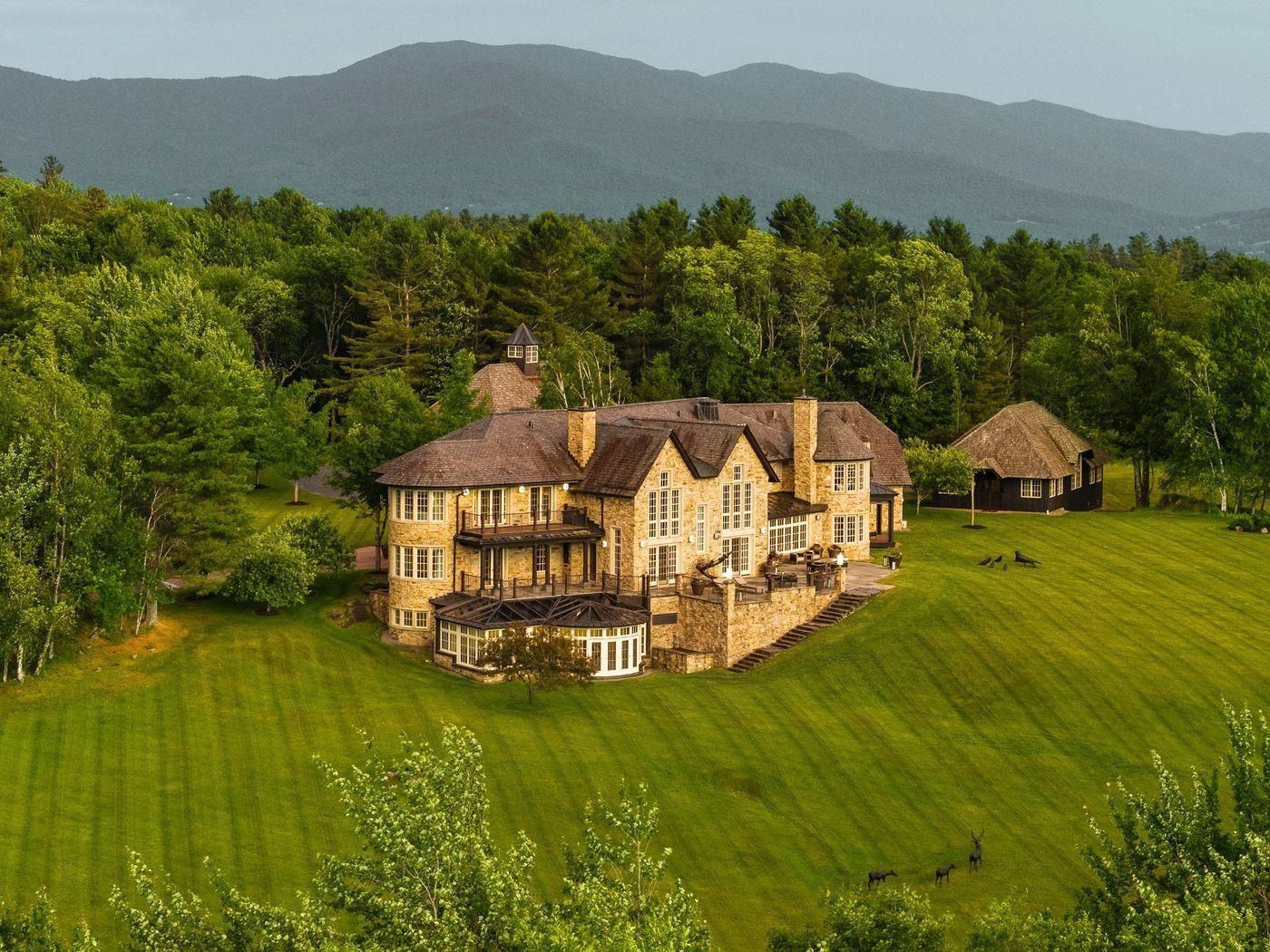 Stone residence at the top of a long mown meadow with mountains behind, 2575 Weeks Hill Road, Stowe, Vermont