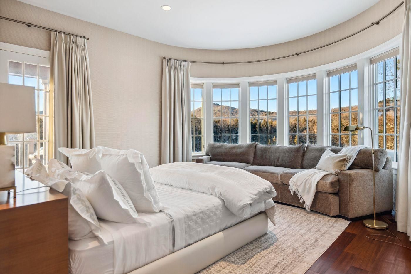 Upper-level bedroom suite with a curved wall of windows and sitting area at 2575 Weeks Hill Road, Stowe, Vermont