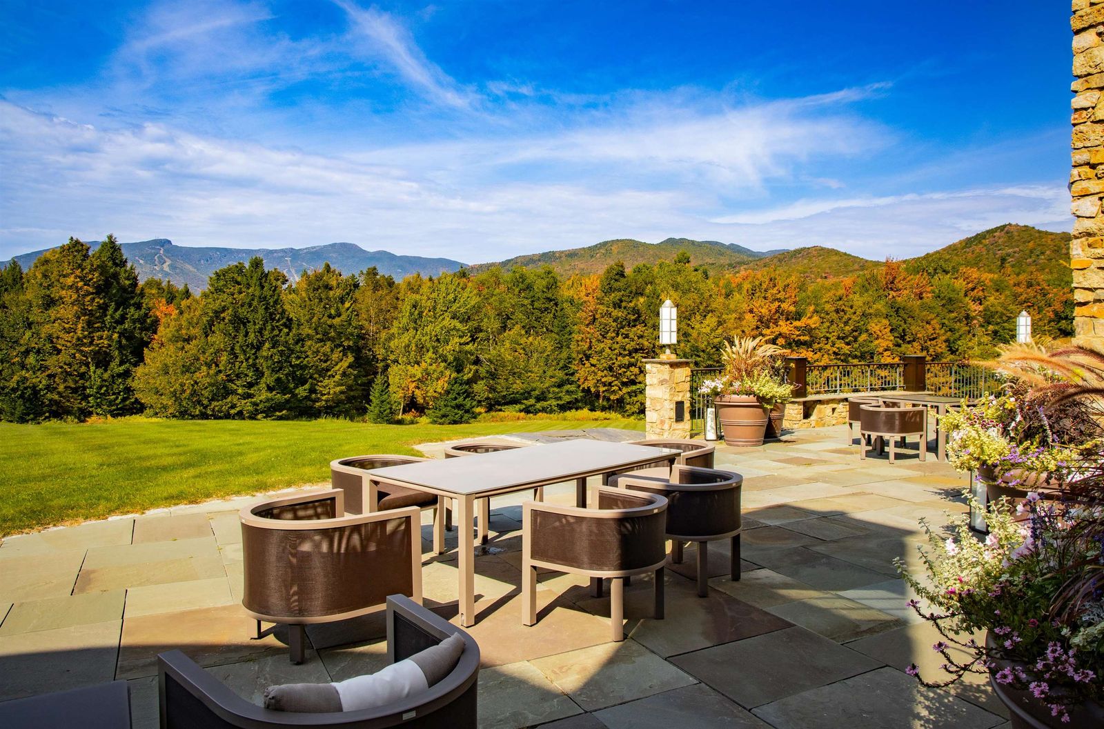 Stone terrace with dining table and seating facing the mountains at 2575 Weeks Hill Road, Stowe, Vermont